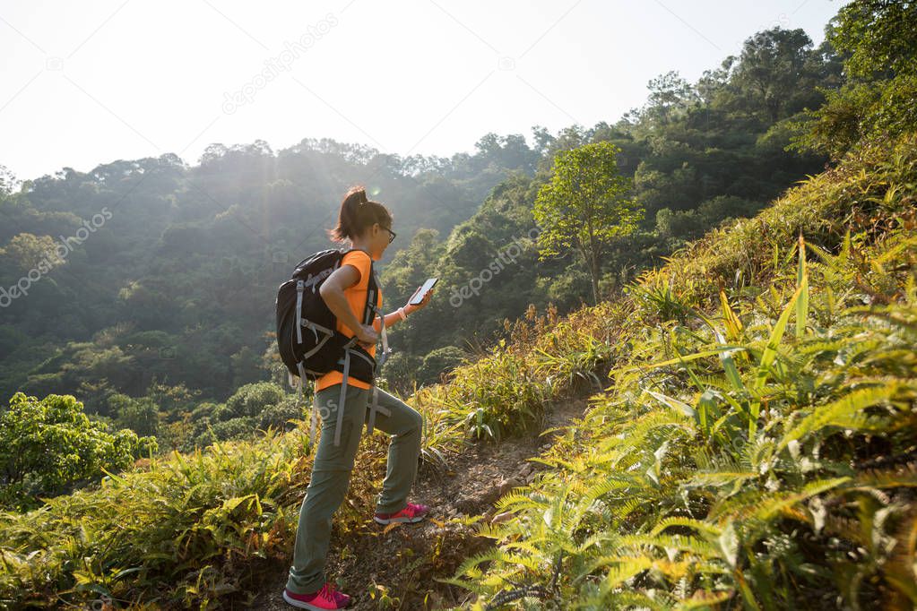 Female hiker using smartphone in autumn forest