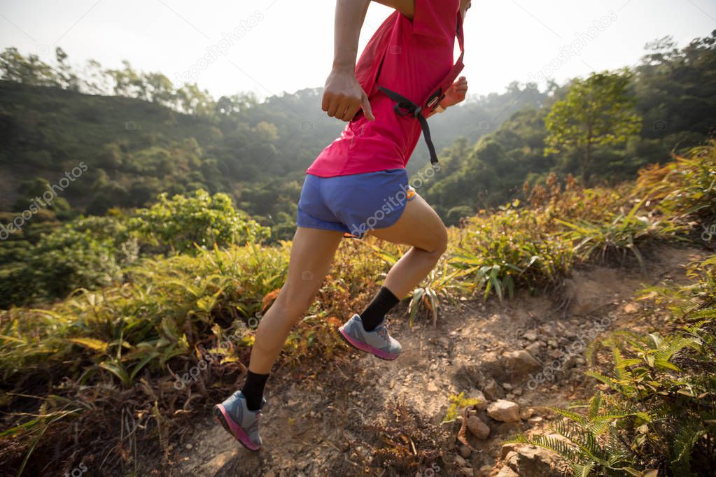 Female trail runner running up on mountain slope in tropical forest