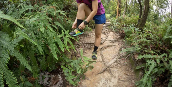 女赛跑选手在森林小径上绑鞋带 — 图库照片