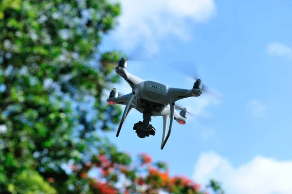 White drone with camera flying in summer garden