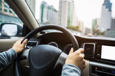 Şehir yolunda araba sürerken direksiyonu tutan eller