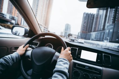 Şehir yolunda araba sürerken direksiyonu tutan eller