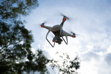 Yaz dağlarında fırtına bulutlarının altında uçan kameralı beyaz dron.