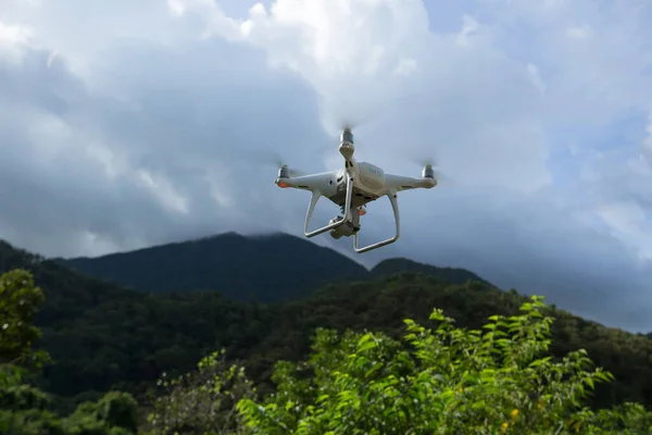 White drone with camera flying in summer mountains under storm clouds