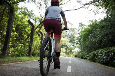 Güneşli bir günde parkta bisiklet süren bir kadın.