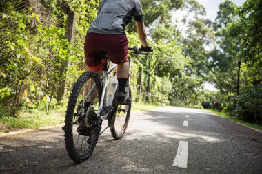 Güneşli bir günde parkta bisiklet süren bir kadın.