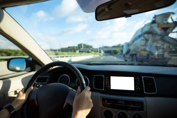 People hands holding steering wheel while driving car on city road