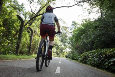 Güneşli bir günde parkta bisiklet süren bir kadın.