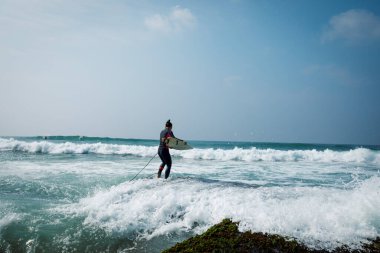 Sörf tahtası olan bir kadın deniz kenarında sörf yapacak.