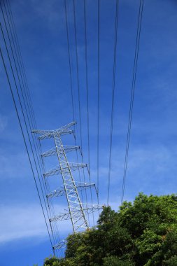 Mavi gökyüzüne karşı yüksek voltajlı elektrik hattı