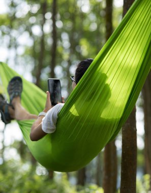 Tropikal yağmur ormanlarında akıllı telefon kullanarak hamakta dinlenmek
