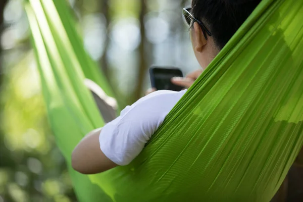 熱帯雨林でスマートフォンを使用してハンモックの手でリラックス — ストック写真
