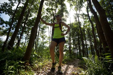 Genç bayan koşucu tropikal ormanda koşarken dinleniyor.