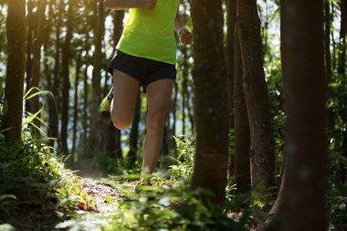 Tropikal ormanda koşan genç bir kadın koşucu.