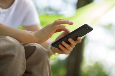 Tropikal ormanda akıllı telefon kullanarak hamakta dinleniyor.