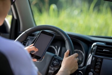 Kadın sürücü, doğada off-road araba kullanırken akıllı telefon kullanıyor.
