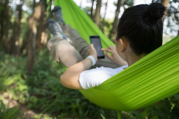 热带森林中使用智能手机在吊床上放松 — 图库照片