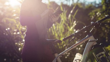 Bisikletçi orman yolunda dağ bisikleti sürerken navigasyon için akıllı telefon kullanır