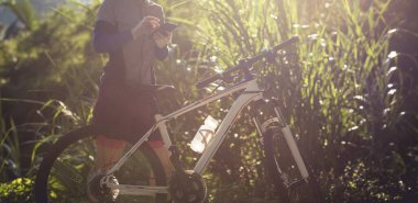 Bisikletçi orman yolunda dağ bisikleti sürerken navigasyon için akıllı telefon kullanır