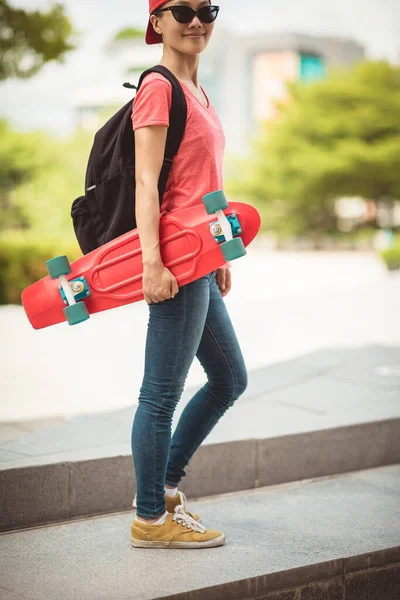 在现代城市里玩滑板的亚洲女人 — 图库照片
