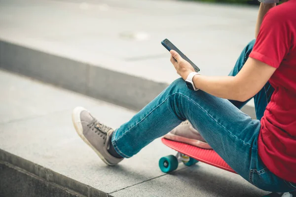 在现代城市 亚洲妇女使用智能手机坐在滑板上 — 图库照片