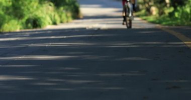 Güneşli bir günde dağ yolunda bisiklet süren bir kadın.