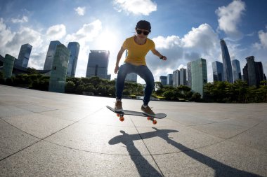 Modern şehirde Asyalı kaykaycı kadın.