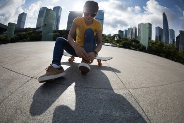 Şehirde ayakkabı bağı bağlayan kaykaycı.