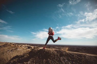 Spor salonundaki kadın, kum tepelerinde koşan bir koşucuyu takip ediyor.