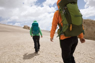 Kum çölünde yürüyüş yapan iki kadın.