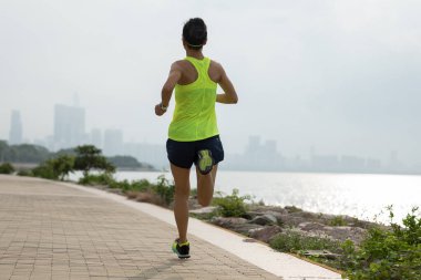 Spor salonundaki kadın güneşli sahil yolunda maratona hazırlanıyor.