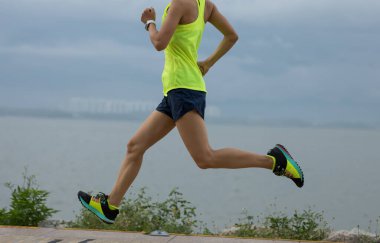 Spor salonundaki kadın güneşli sahil yolunda maratona hazırlanıyor.