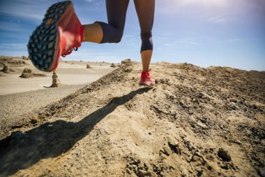 Fitness kadını, kum çölünde koşan bir koşucunun izini sürüyor.