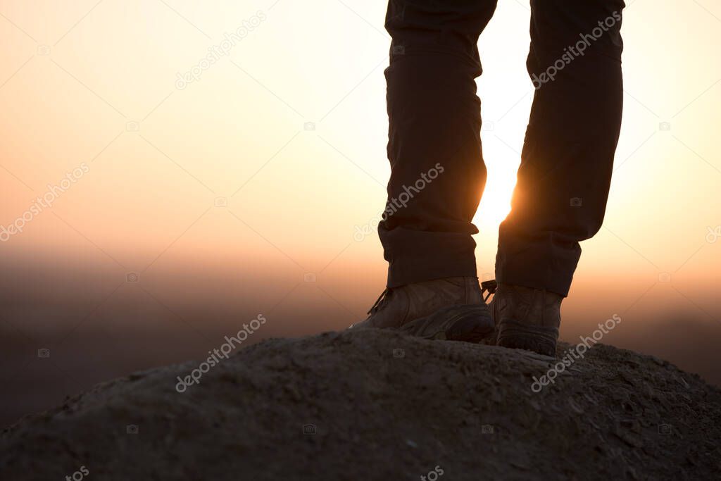 Successful woman hiker enjoy the view on sand desert in the sunset