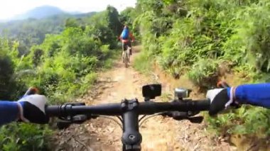 Tropikal ormanda iki arkadaş dağ bisikletini geçiyor.