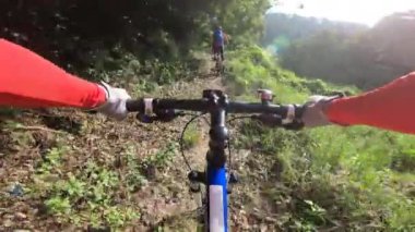 Tropikal ormanda iki arkadaş dağ bisikletini geçiyor.