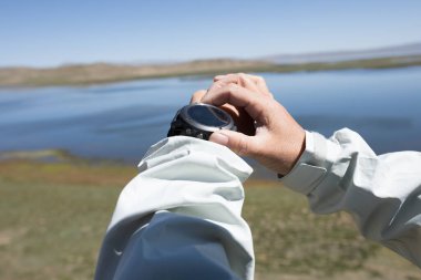 Yürüyüşçü kadın, spor saatinin yüksekliğini kontrol ediyor. 