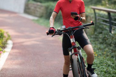 Bisiklet sürmek, güneşli bir günde bisiklet sürerken akıllı telefon kullanmak