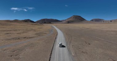 Yüksek irtifada göl kenarında çalışan off-road aracının hava görüntüleri.