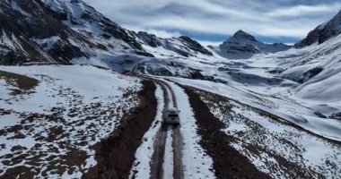 Yalnız bir araç karlı bir dağ yolunda ilerliyor..