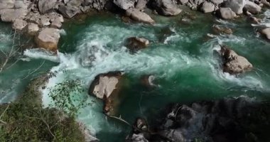 Bir video, büyük kayaların etrafında akan bir nehrin kristal berrak suyunu yakalar..