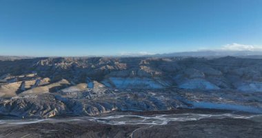 Geniş, mavi gökyüzünün altında karlı bir kanyonun yüksek açılı videosu..