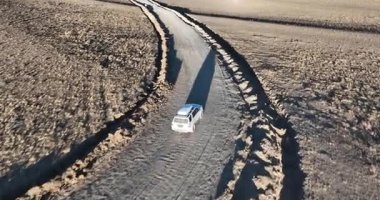 Bir İHA videosu, kurak bir arazide uzun toprak bir yolda seyahat eden bir aracı yakalar..