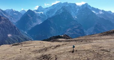 Sırt çantalı bir kadının yüksek rakımlı bir dağın tepesinde yürüyüş yaparken çekilmiş görüntüleri. 