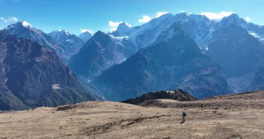 Sırt çantalı bir kadının yüksek rakımlı bir dağın tepesinde yürüyüş yaparken çekilmiş görüntüleri. 