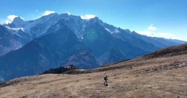 Sırt çantalı bir kadının yüksek rakımlı bir dağın tepesinde yürüyüş yaparken çekilmiş görüntüleri. 