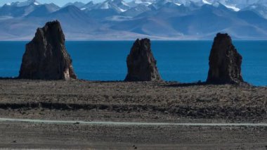 Yüksek açılı bir videoda engebeli, turkuaz bir göl ve kayalık bir uçurumun yanında.