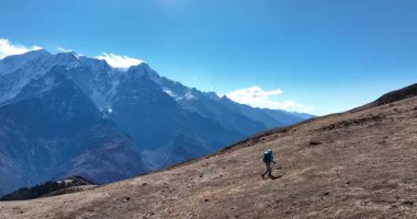 Yavaş çekim videosu. Sırt çantalı bir kadının yüksek irtifada dağ tepesinde yürüyüşünü gösteren hava görüntüleri. 