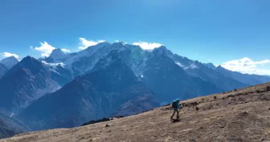 Sırt çantalı bir kadının yüksek rakımlı bir dağın tepesinde yürüyüş yaparken çekilmiş görüntüleri. 