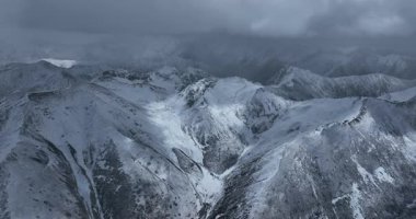Karla kaplı güzel yüksek irtifa dağlarının hava görüntüleri. Bulutlu gökyüzü 